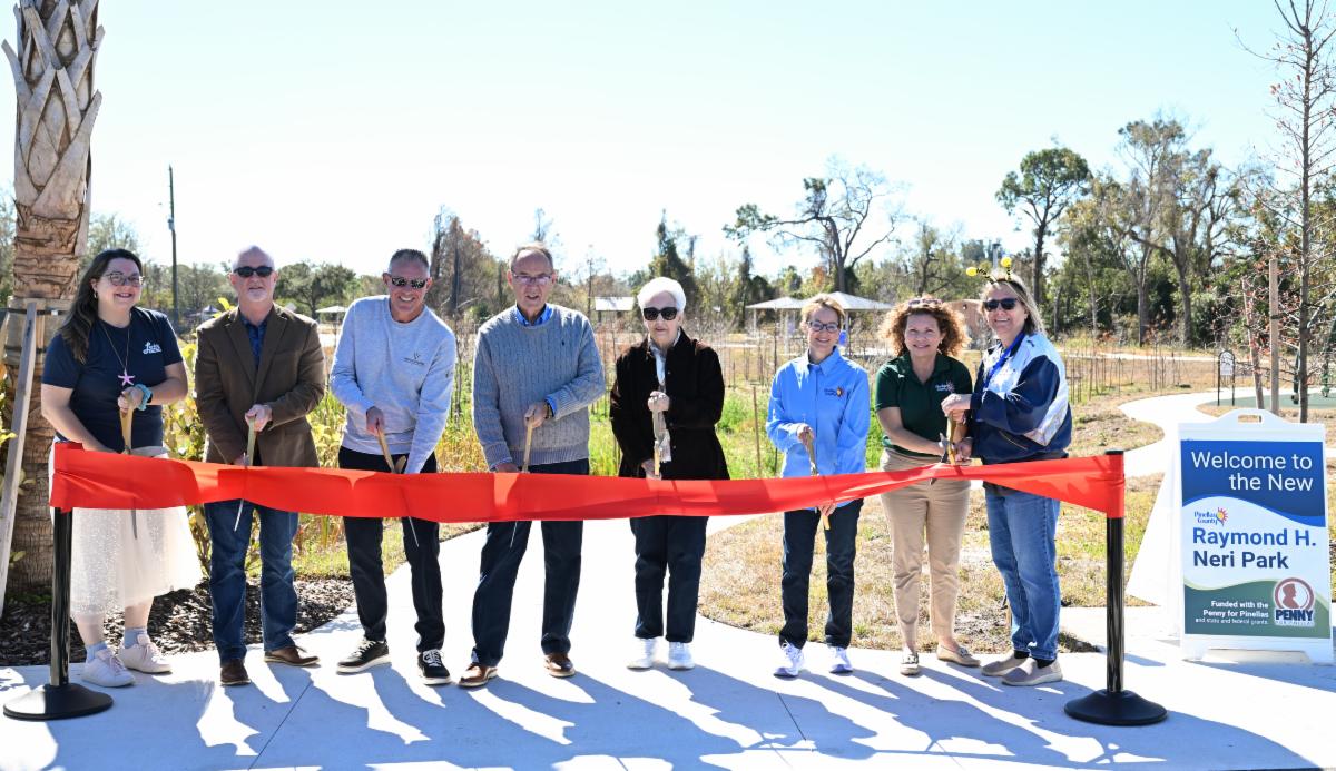 Pinellas County and community leadership pose with scissors behind a red ribbon