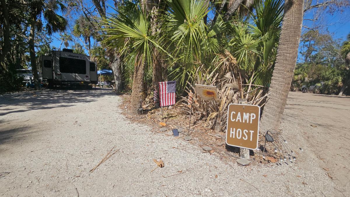 Photo of the Fort De Soto campground and welcoming sign reading "camp host" next to an American flag.