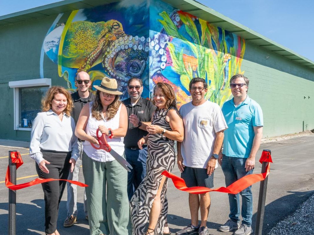 Lealman CRA team cutting ribbon in front a mural of an octopus on the corner of the building