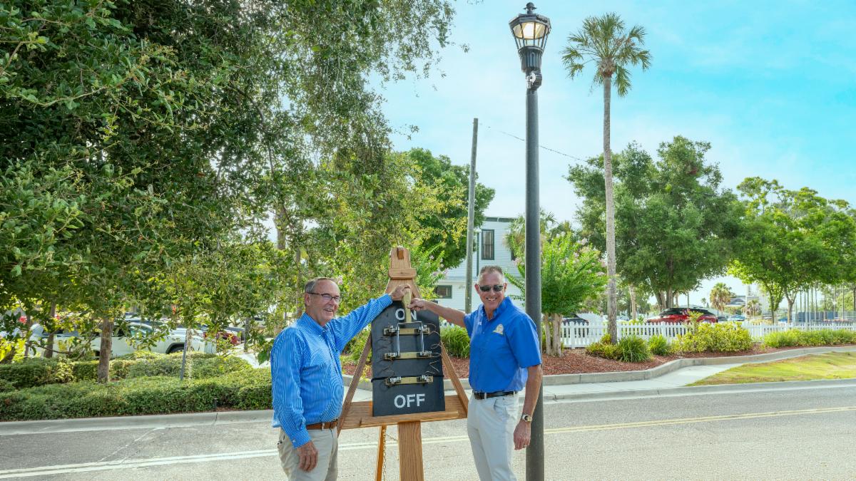 BCC Chair Dave Eggers and Commissioner Brian Scott flip a giant mock switch to the ON position for a street light illuminated behind them.