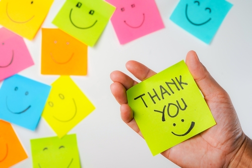 Thank you and smile icon inspirational handwriting on sticky notes on hand held