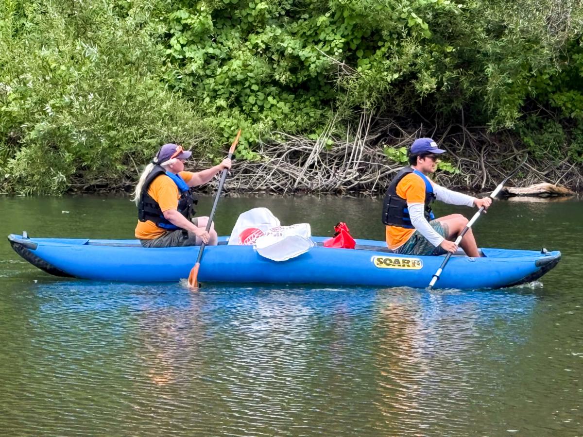 two people rowing a blue canoe on the river.
