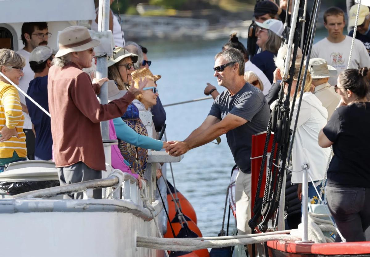 Onboard the tall ship Providence, Richard Clarke, welcomes visitors on the Nootka Rose, from Orcas Island, with a handshake.