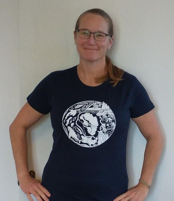 Cindy Elliser standing in front of a white background with a dark blue t-shirt bearing the SSI logo on the chest.