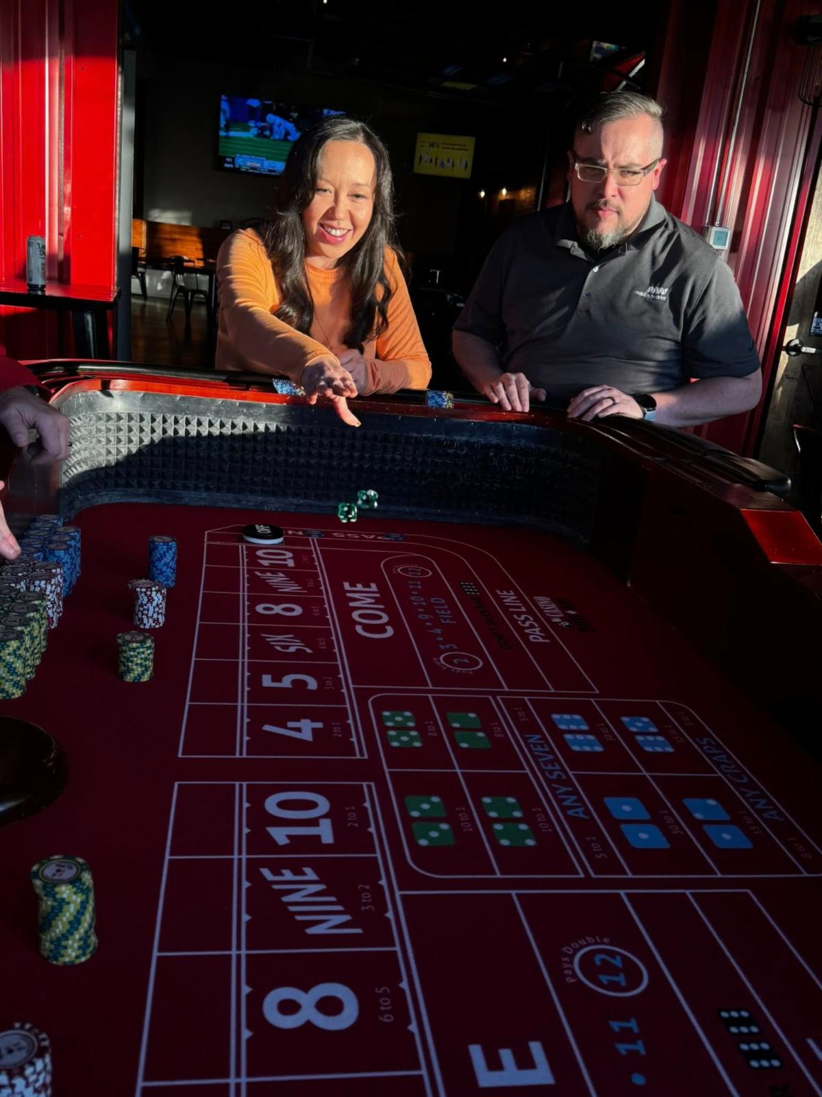 A woman throws dice while playing craps.