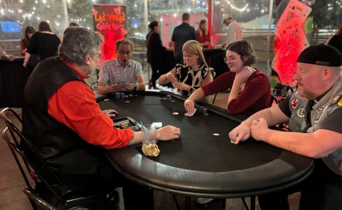 	• Group of people sitting around a table playing poker at a casino night event.