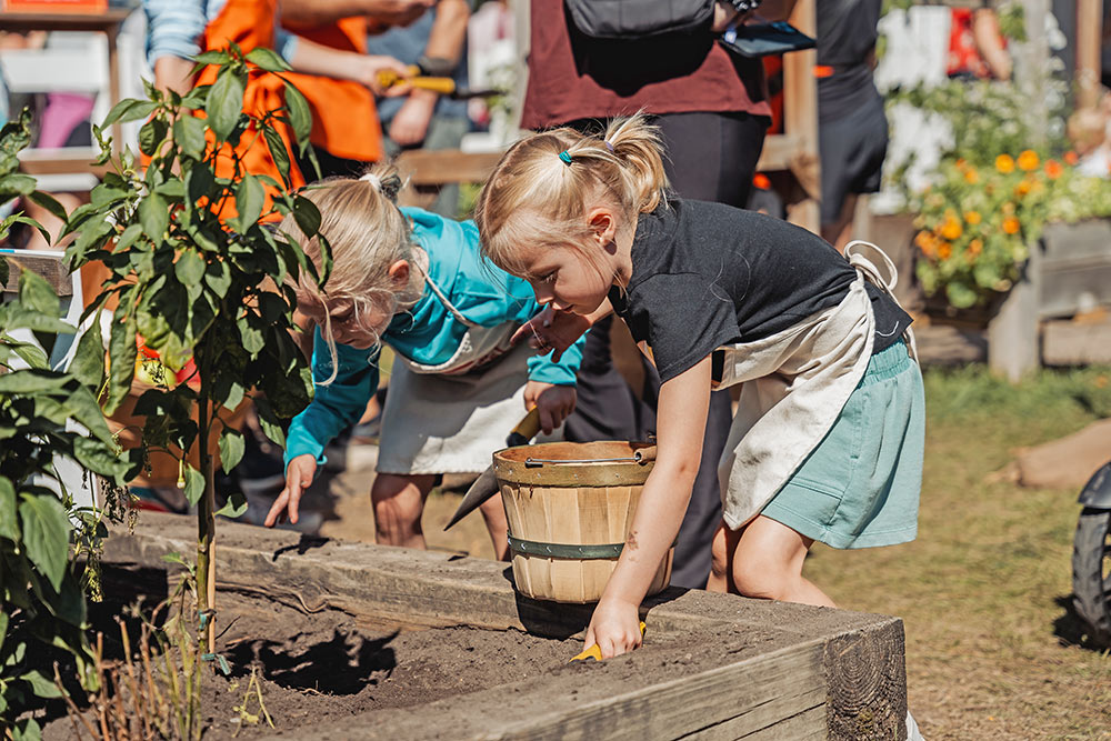 Two young girls dig in the dirt at the Little Farm Hands exhibit