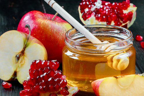 Jewish religious holiday Rosh Hashanah. Still life of apples_ pomegranates and honey on a dark wooden background. Traditional symbols of celebration