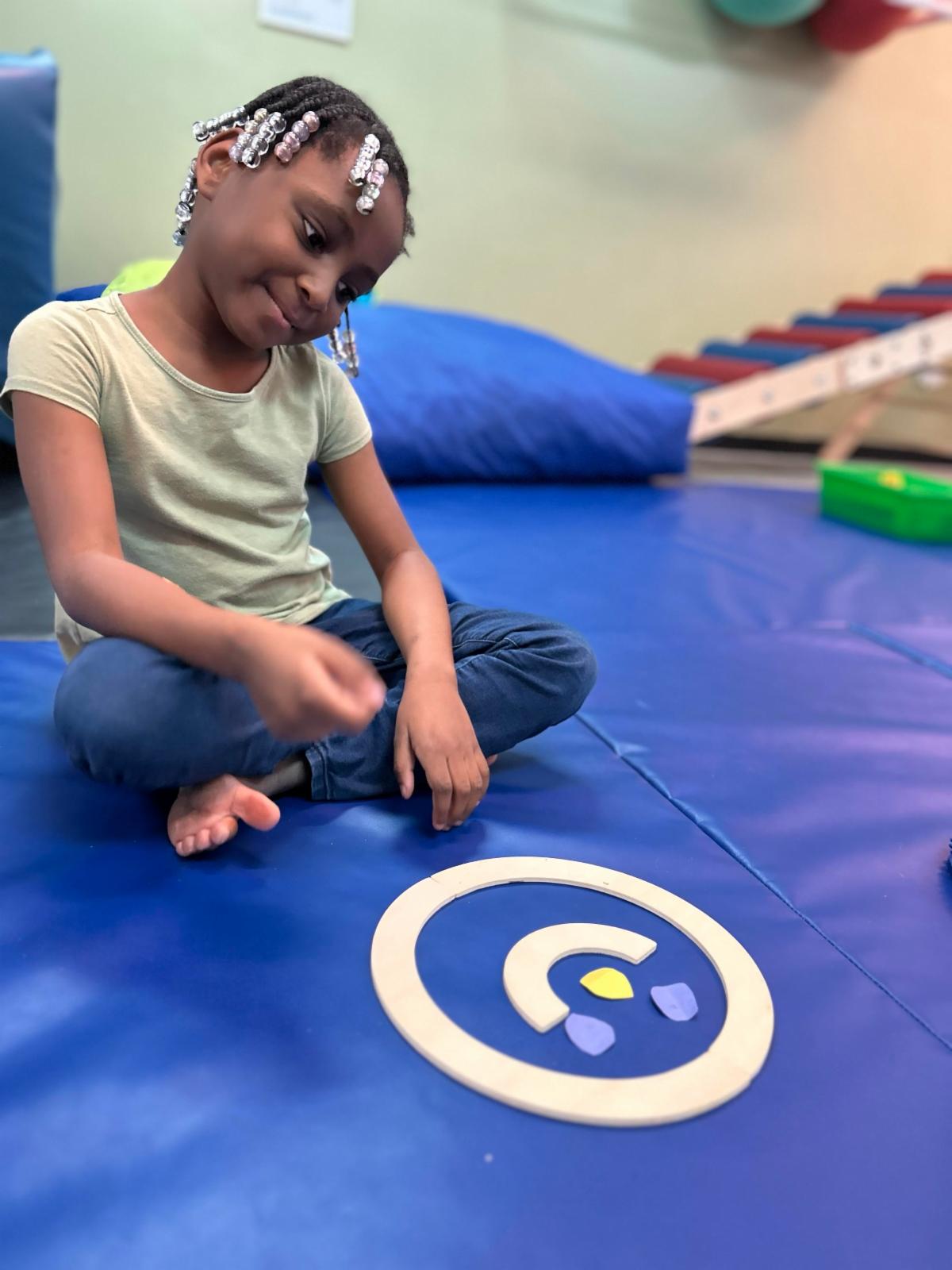 SPED student looking at smiley face occupational therapy on a blue mat
