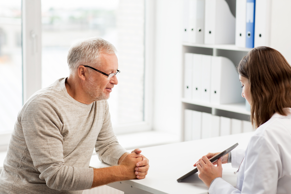 female doctor showing older white man tablet