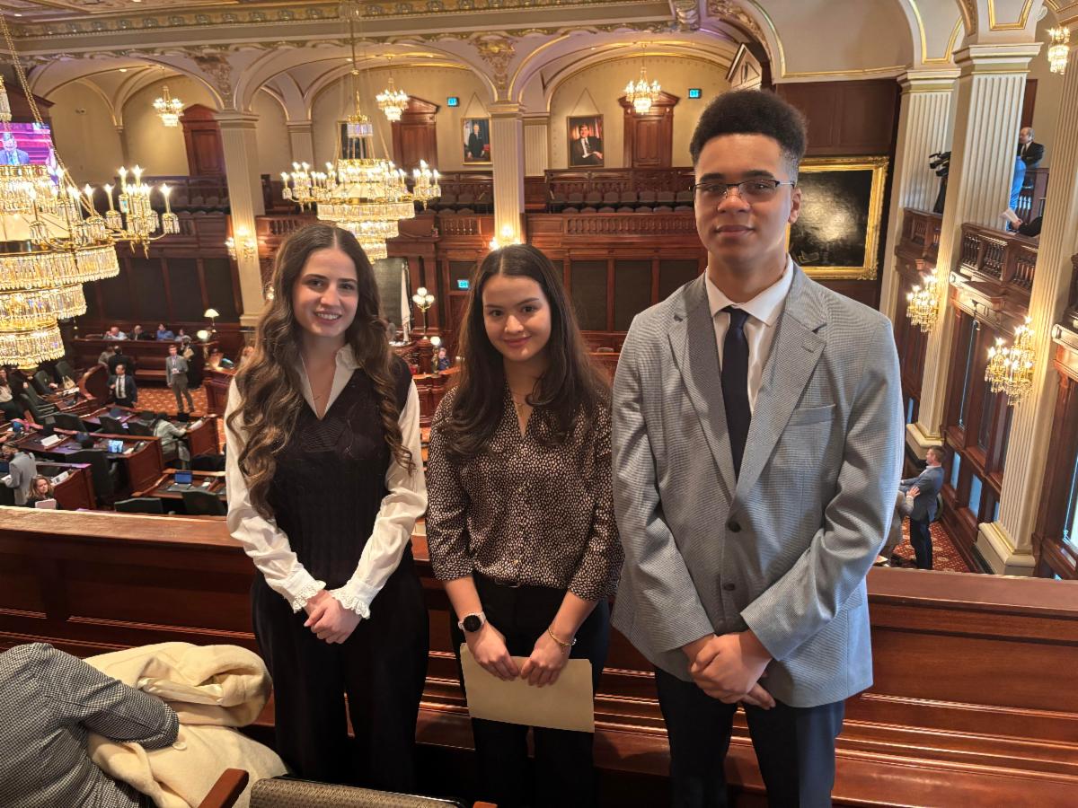 Students in buiness professional attire pose for a photo in the illinois state capitol