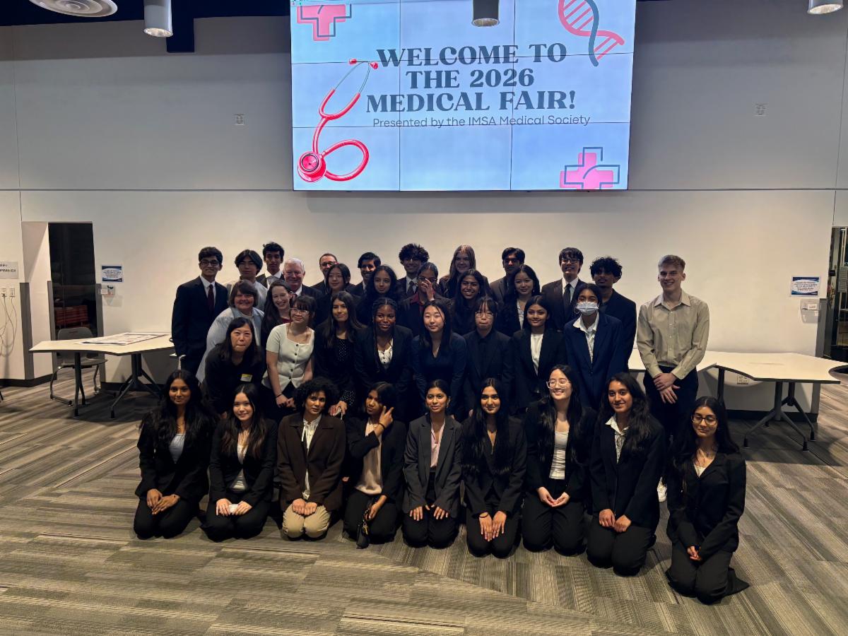 A group of students and staff pose for a photo at the 2026 Medical Fair under a welcome display.