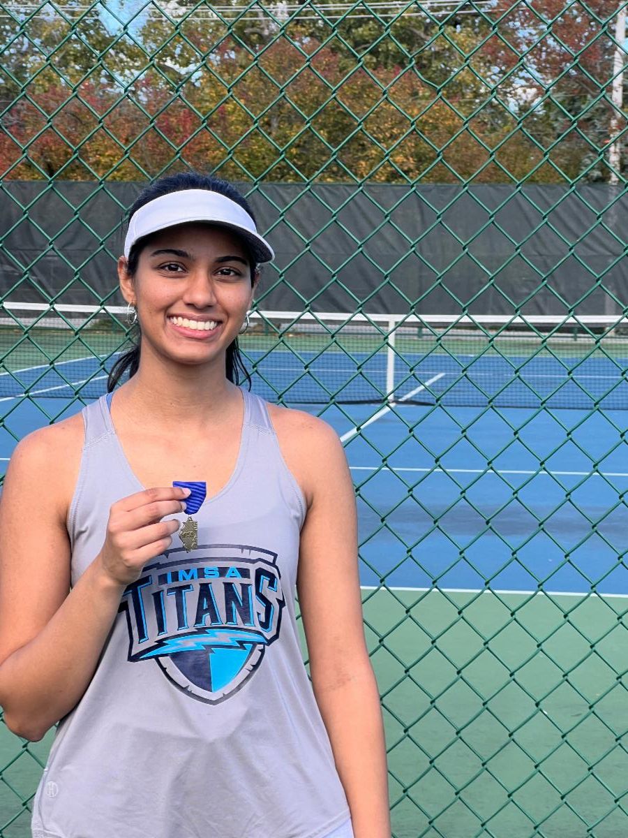 A Titans tennis player poses with her sectional medal on the tennis court