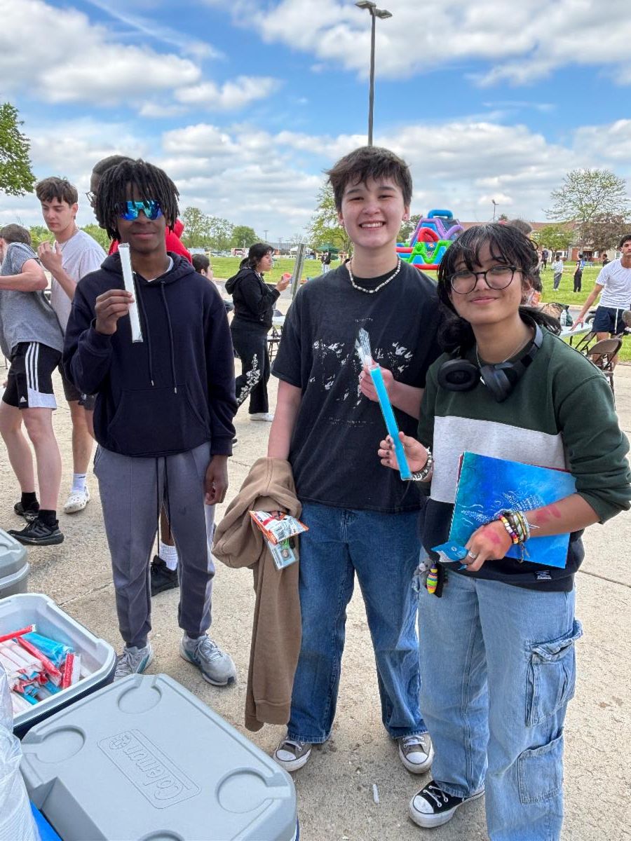 3 students smile while eating popsicles at field day