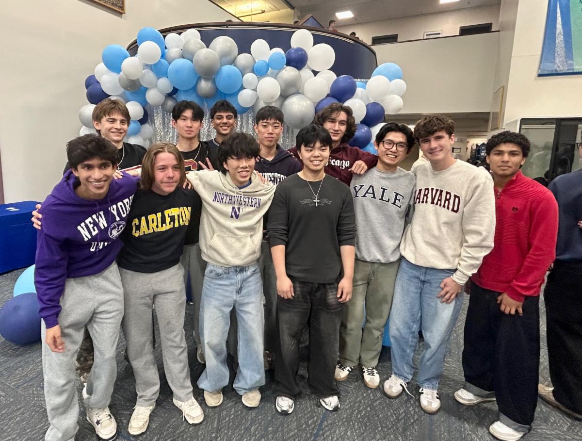 Students pose in college sweatshirts in front of blue and white balloons
