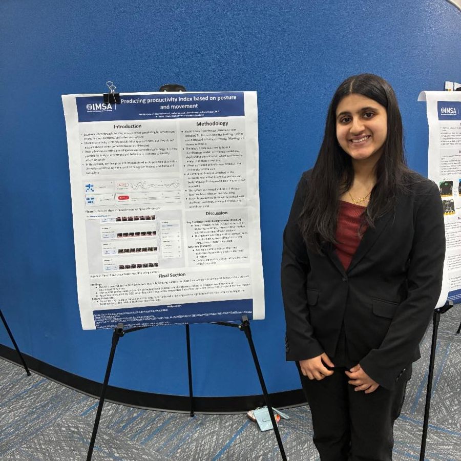 A student stands next to a poster dressed in business professional attire.