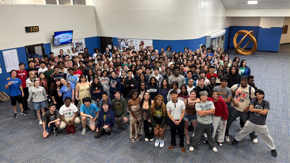 A large group of students pose in college t shirts 