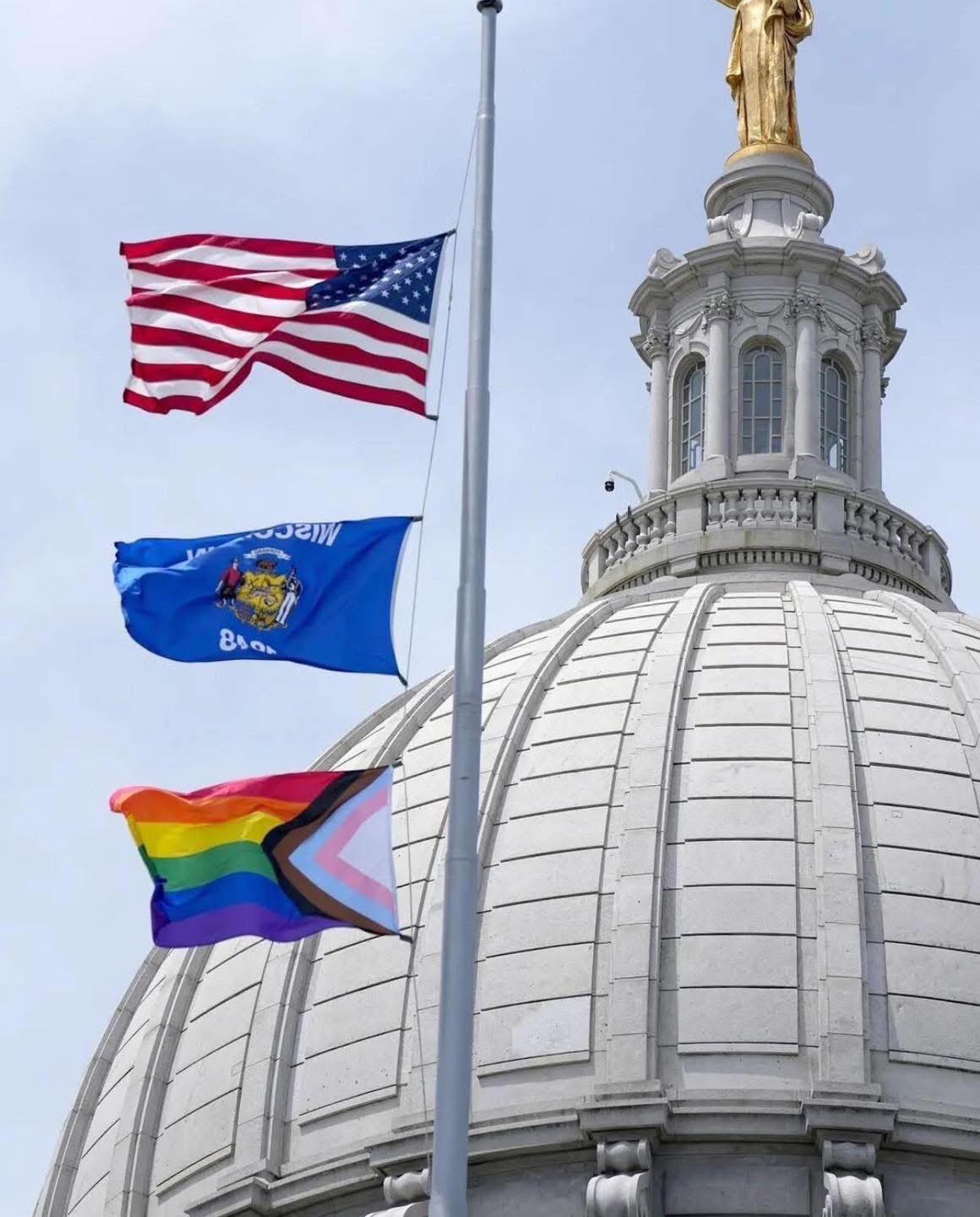 Wisconsin State Capitol dome in June 2026 with US flag, Wisconsin flag, and pride month flag on display