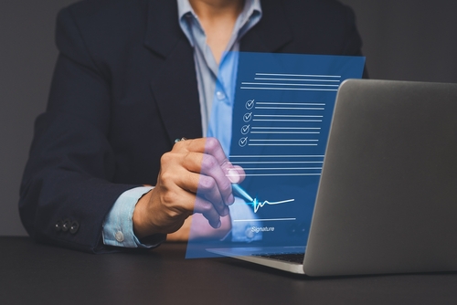 A businessman signing a digital document on a laptop_ representing e-signature_ online agreement_ digital approval_ and modern business workflow.