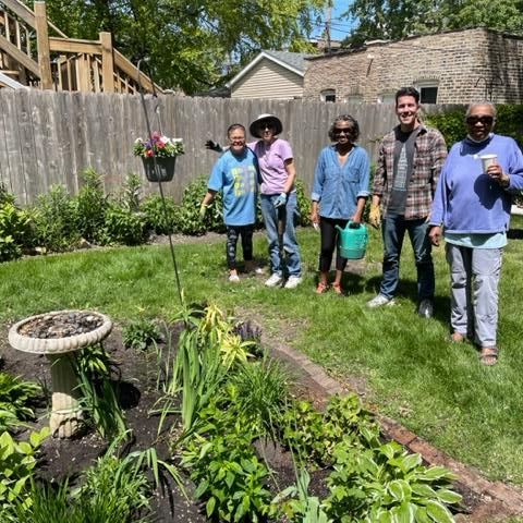 St. Gertrude parishioners who helped plant veggies and herbs smiling and standing together by garden