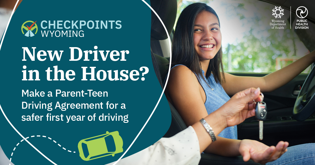 A parent hands a set of car keys to a smiling teenager sitting behind the wheel of a car