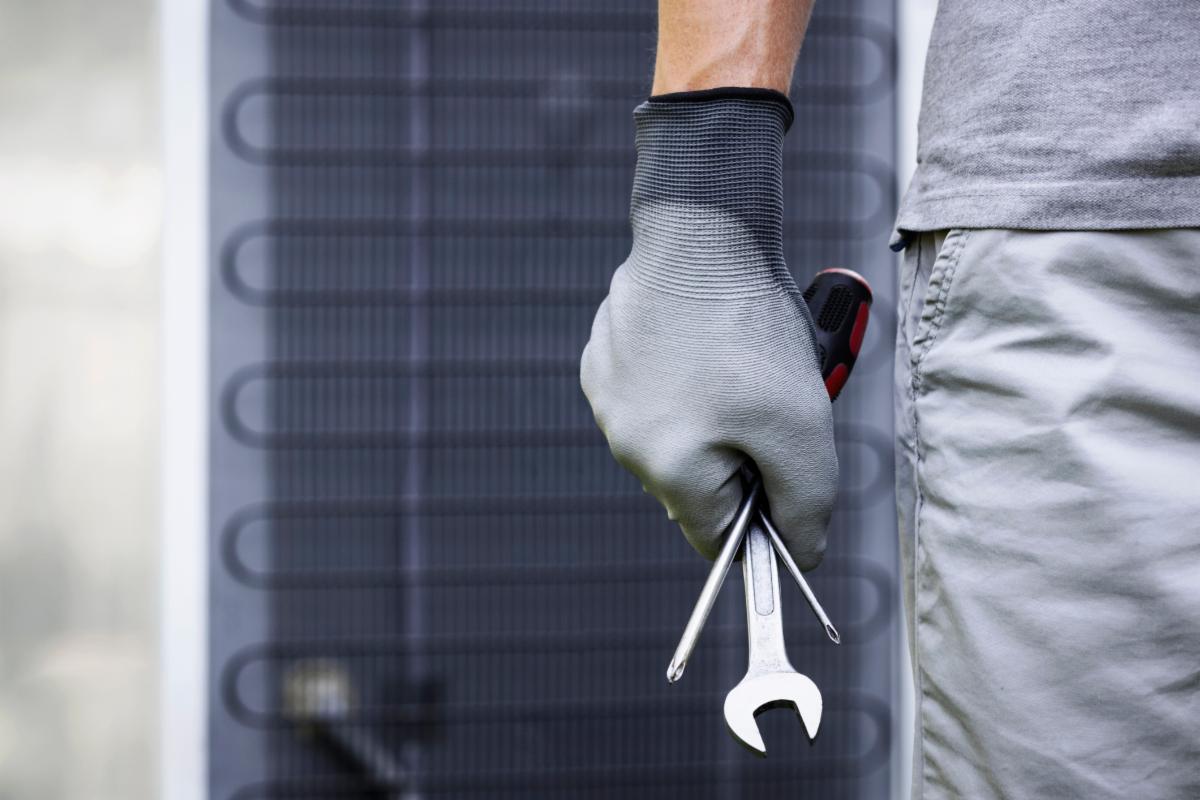 Refrigerator Maintenance. Worker  Hand Servicenan with Tools on Fridge Background. Fridge Services
