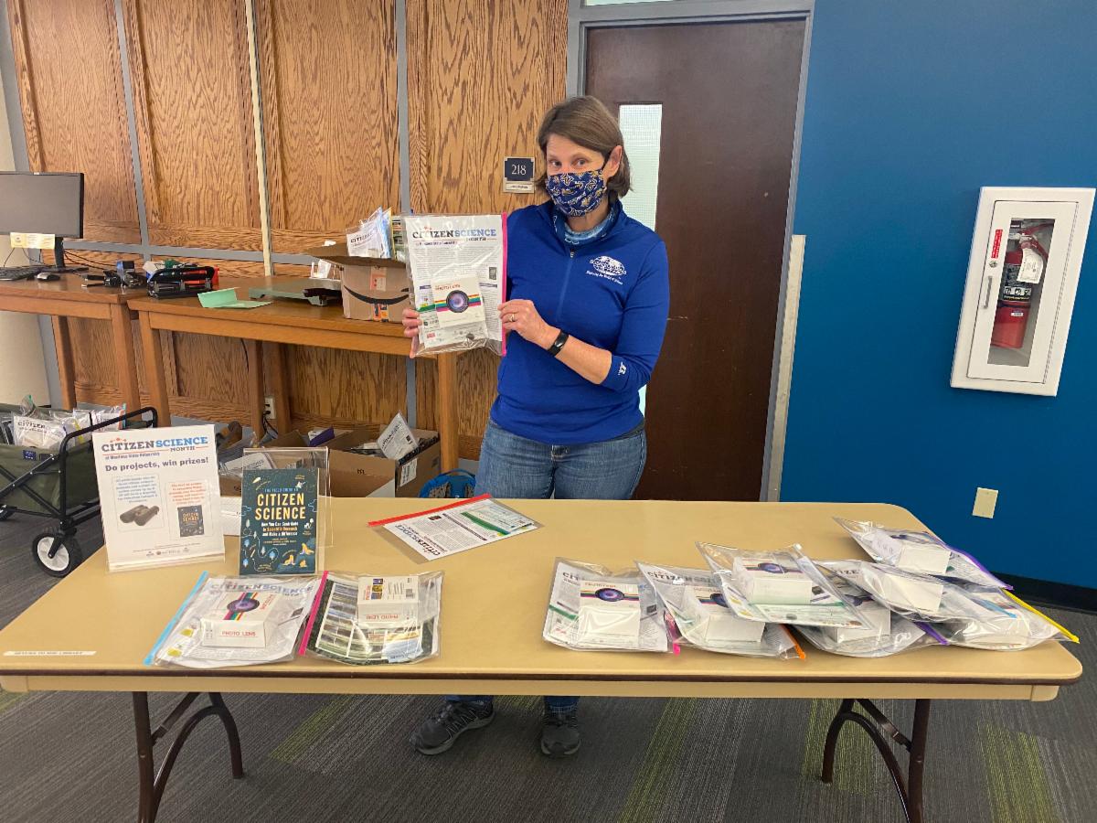 Suzi Taylor from SMRC at MSU standing in front of the Citizen Science kit giveaway table