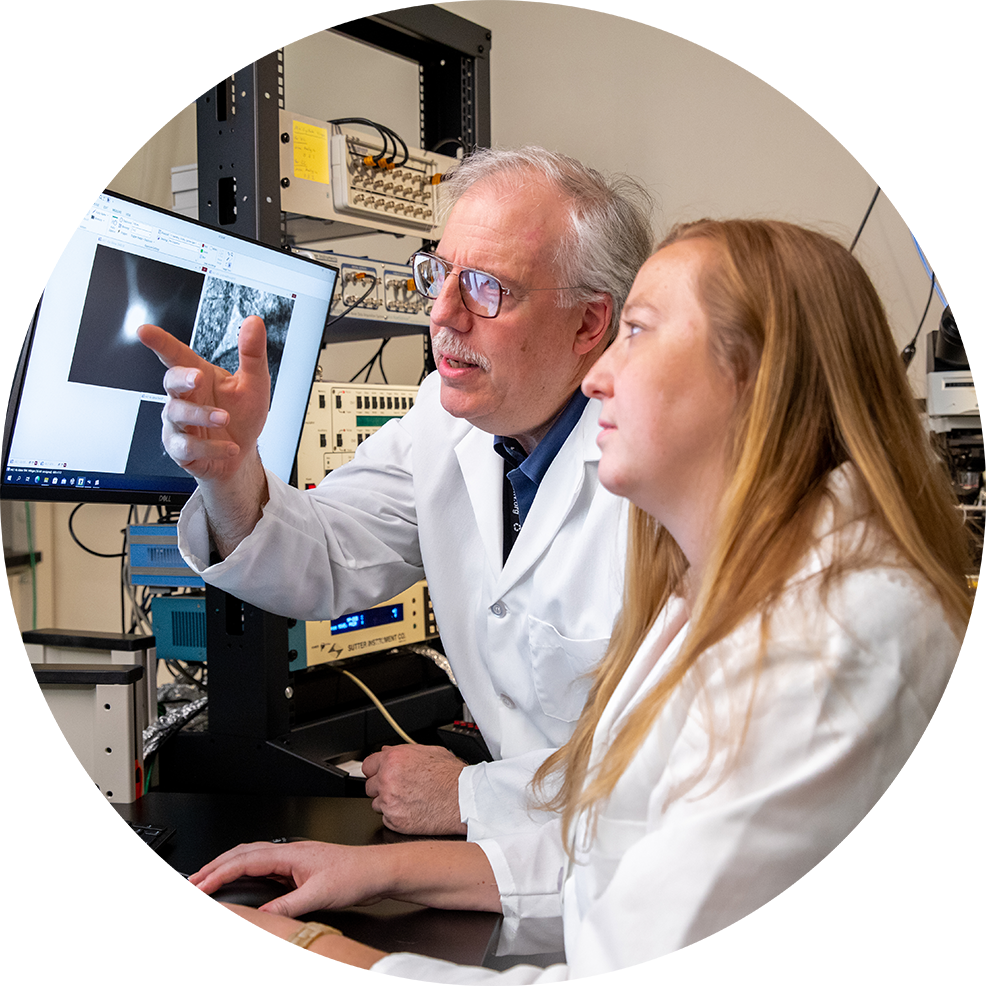 man and woman looking at screen wearing lab coats