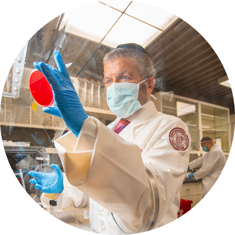 Scientist in a white lab coat looking at a red specimen 