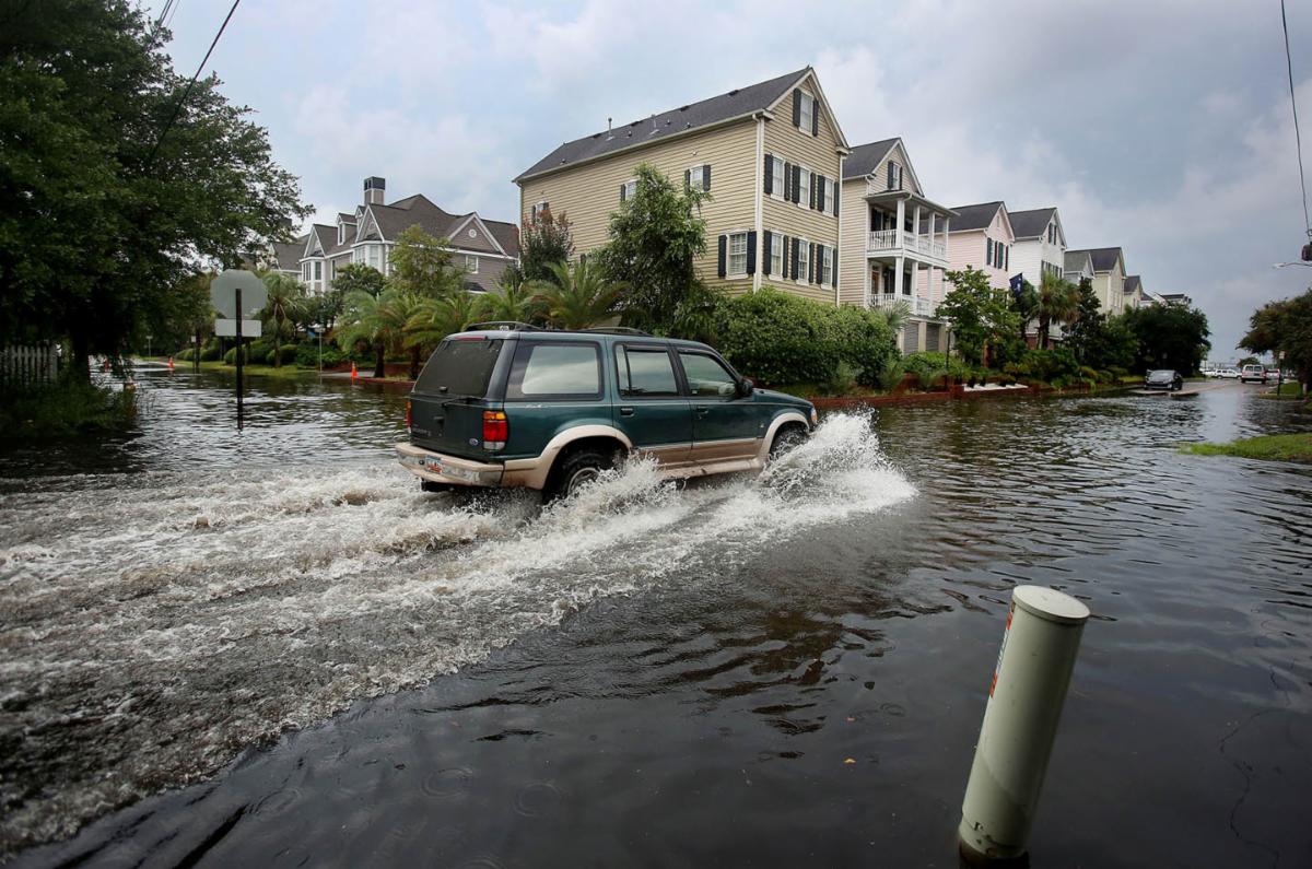 Car driving through a flooded street.