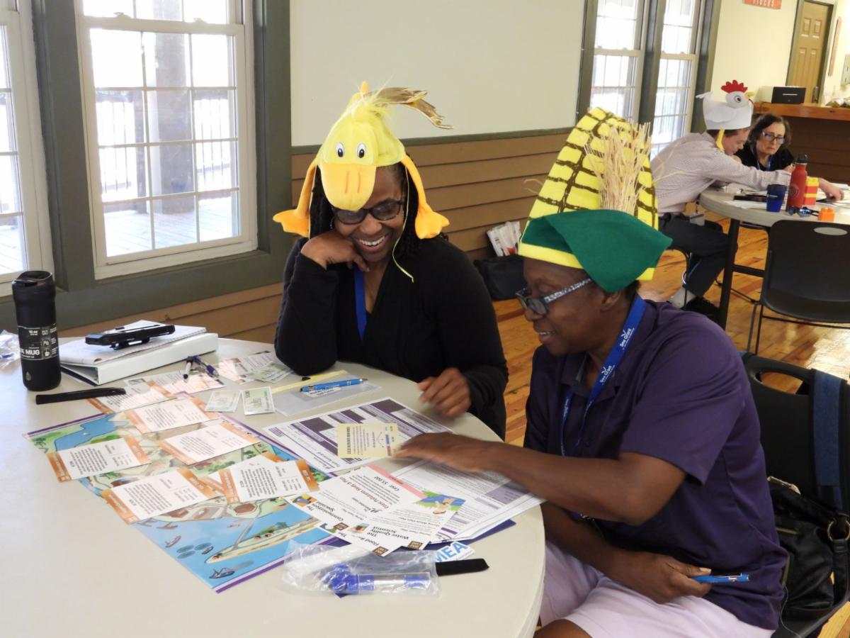 Photo of Wiltress Felder and Angela Kennedy sitting at a table playing The Watershed Game during a workshop