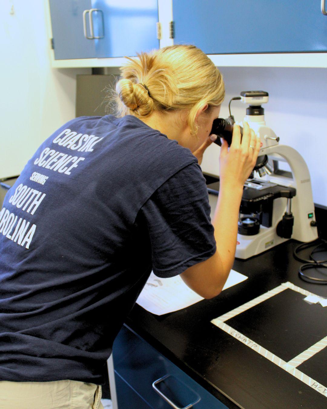 Photo of Mary Lide looking through a microscope at a water sample