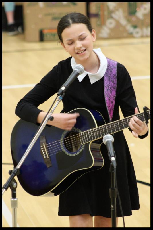 A student playing a guitar and singing