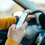 Image showing hand holding a phone while driving.