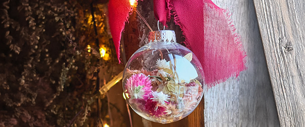 Photo of custom made Christmas ornament glass bulb against a wood and thistle background.