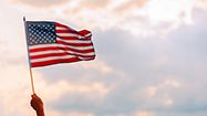 A US flag waves in front of beauitful clouds.