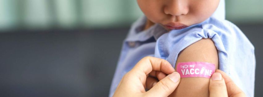 a pink bandage that says 'I got my vaccine' being placed on a toddler's arm
