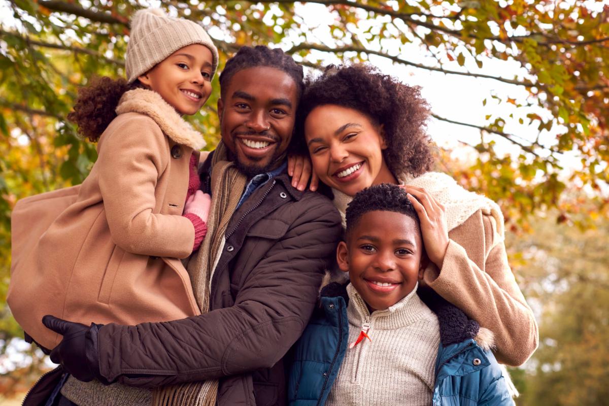 a family smiling in the fall leaves