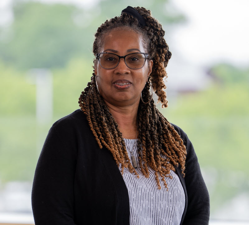 Tawanda Gutrick, Senior Stakeholder Relations Specialist headshot wearing a black sweater with a black and white striped shirt