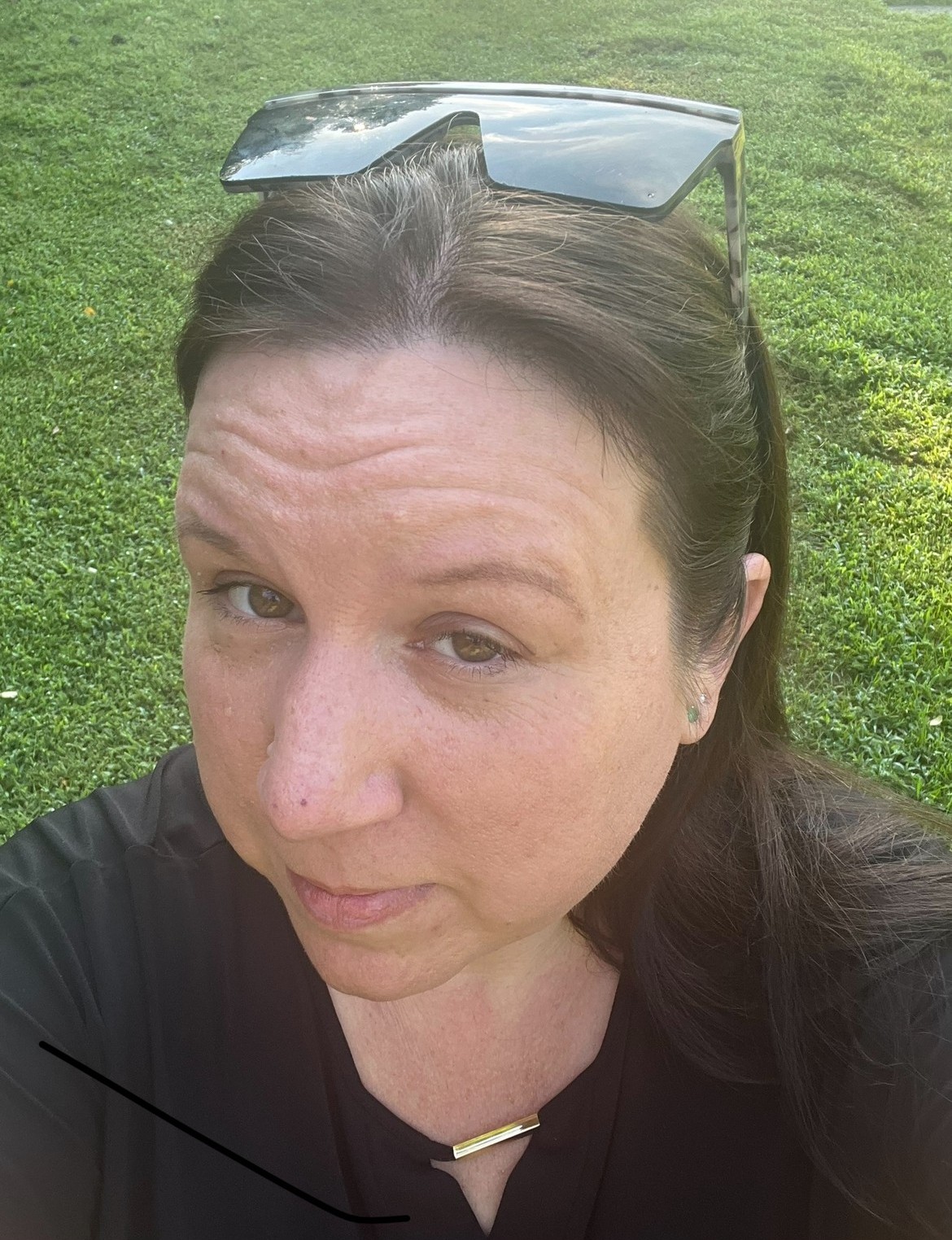 Woman with brown hair wearing sunglasses on top of her and a black shirt