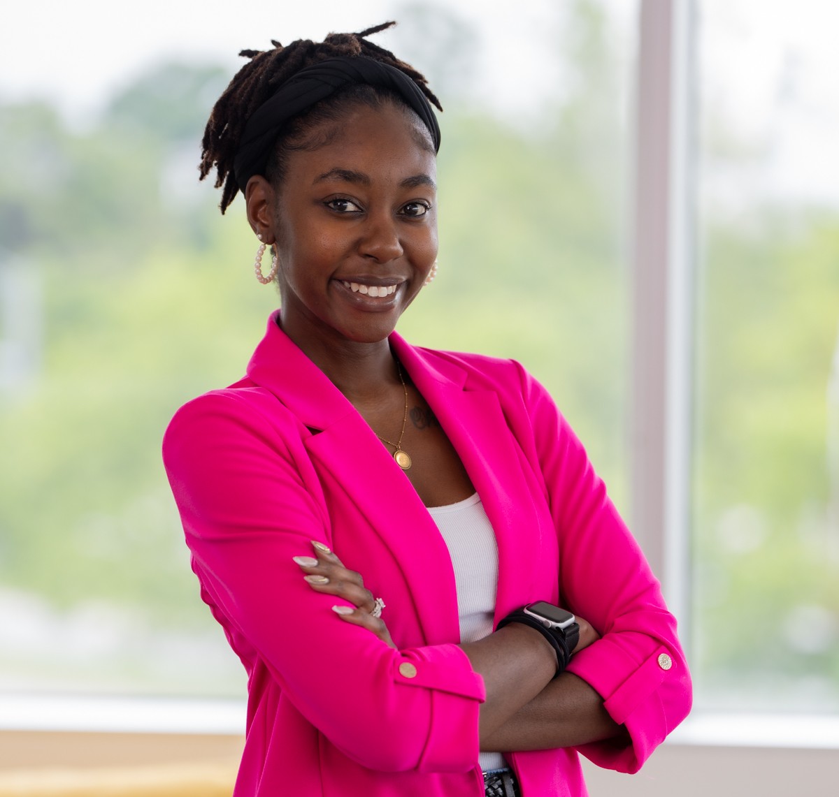 Woman wearing a bright pink blazer posing for a headshot