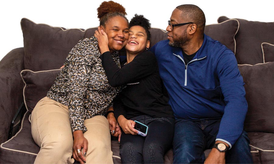 Leonard and LaTrieva smiling on the couch with their daughter Chloe