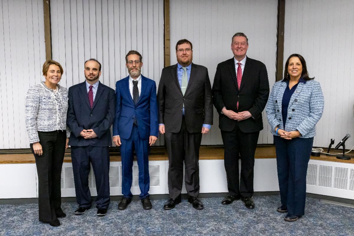 Six adults in business clothing standing and posing for a photo