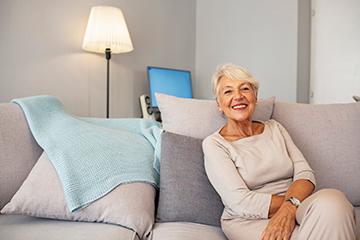 older woman smiling while sitting on a couch