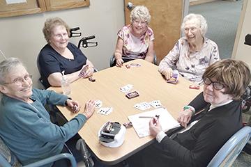 women sitting at a table playing a card game