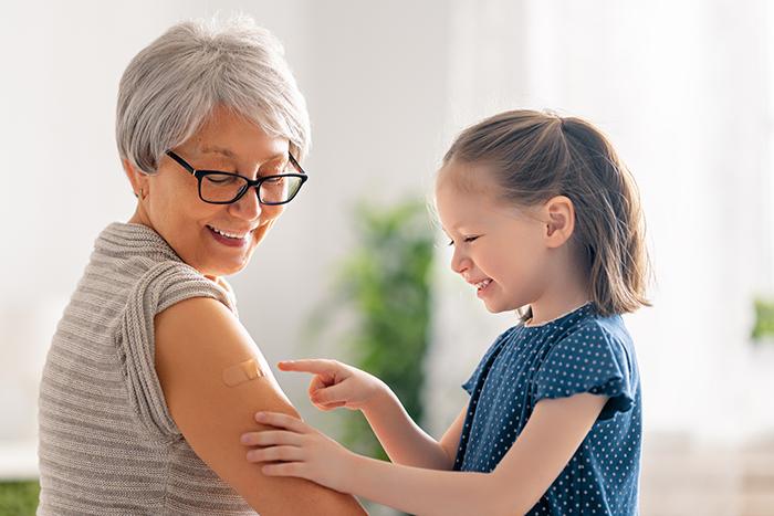 girl pointing to a band-aid on a woman's arm