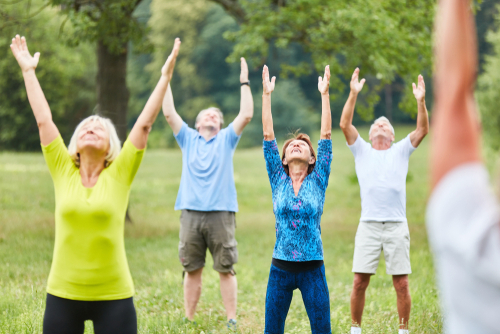 Active seniors doing healthy stretching in a rehabilitation fitness course in summer