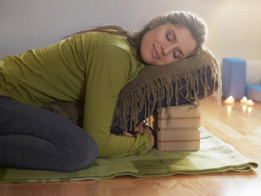 Serene lady relaxing and meditating on a yoga mat in a cosy house