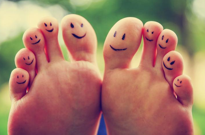 smiley faces on a pair of feet on all ten toes  VERY SHALLOW DOF - big toe on the right  in a park setting toned with a retro vintage instagram filter app or action effect