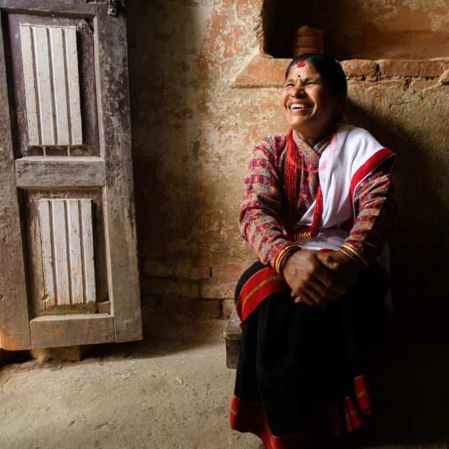 Woman in a bright red sari sitting in a doorway in Nepal